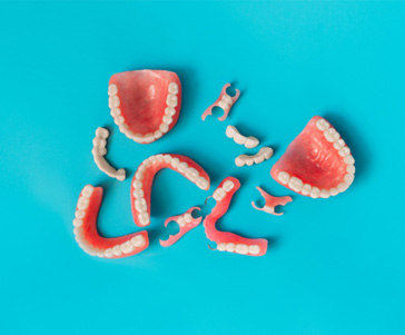 Bird’s eye view of several full and partial dentures with light blue background